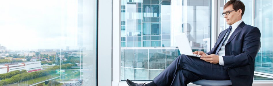 Man sitting in front of window looking at his laptop